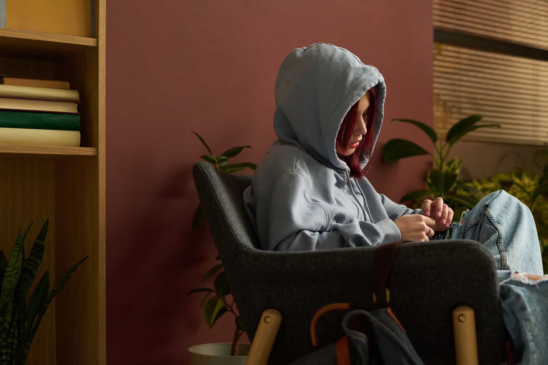 ADHS und Borderline symbolisiert durch eine junge Frau, die sich in einem Sessel zurückzieht