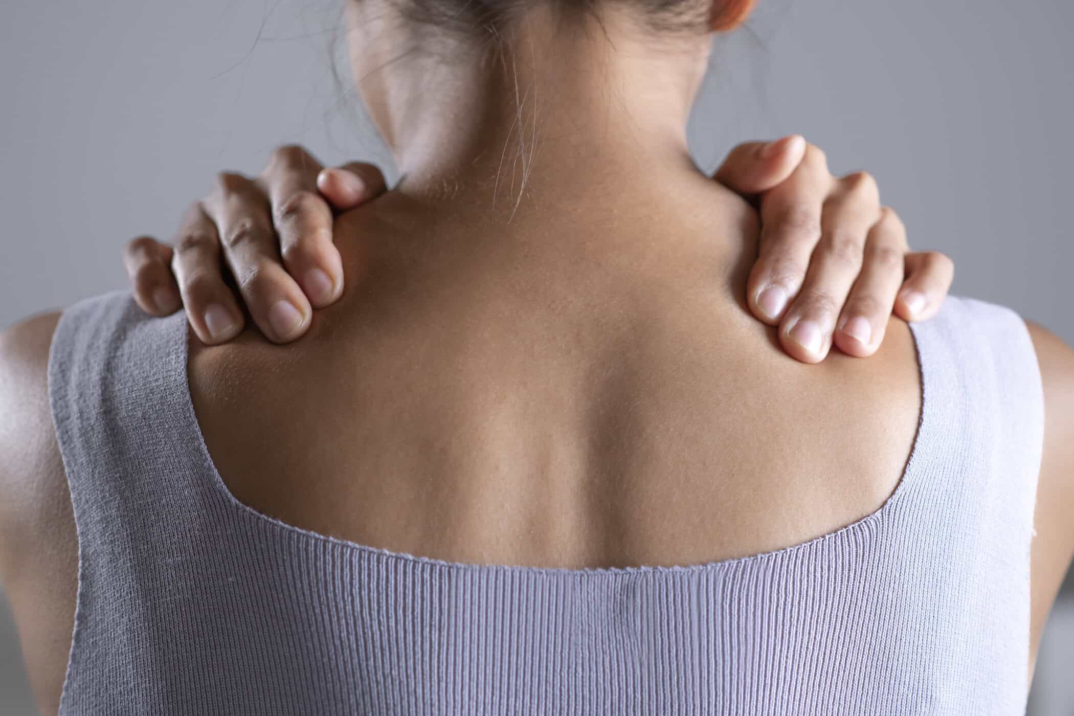 Eine Frau massiert ihre Schultern mit ihren Händen, symbolisiert ADHS und Fibromyalgie