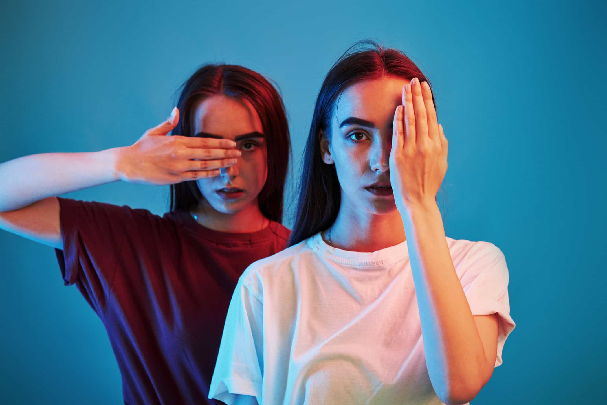 Zwei Frauen in rotem und blauem Licht verdecken sich je ein Auge und symbolisieren die verschwimmenden Grenzen zwischen ADHS und Bipolarer Störung