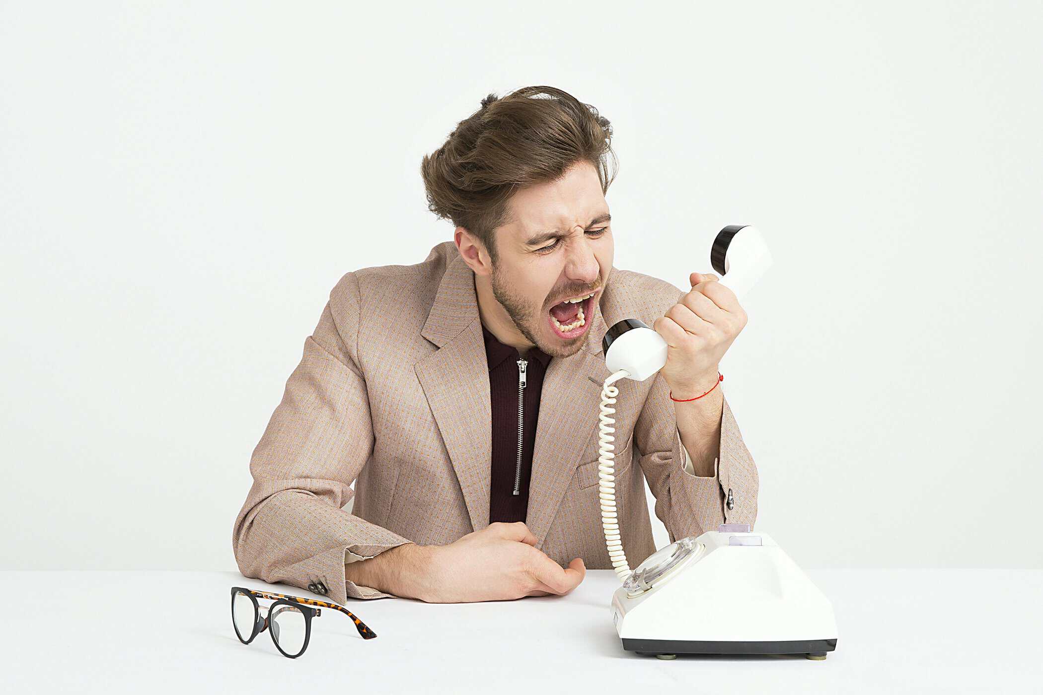 Man sitting on desk, angry screaming in phone