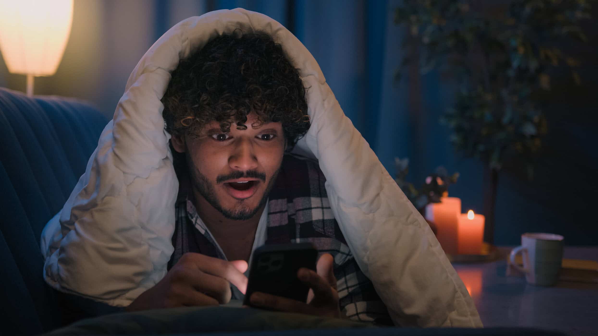 Junger Mann nutzt nachts sein Smartphone im Bett – Symbolbild für ADHS und Schlaf, innere Unruhe, spätes Wachbleiben und Schwierigkeiten beim Abschalten.