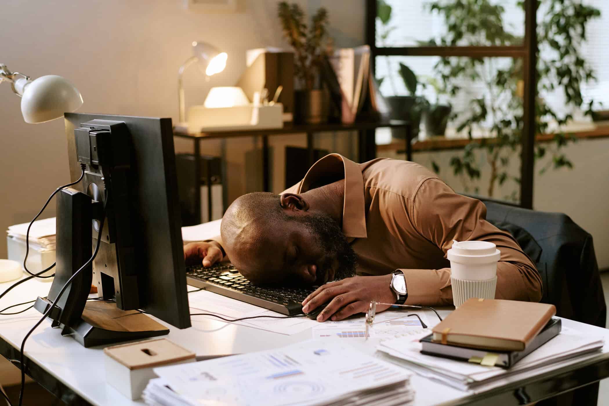 ADHS und stress: Exhausted man sleeping at office desk as a symbol of chronic overload and mental exhaustion associated with ADHD