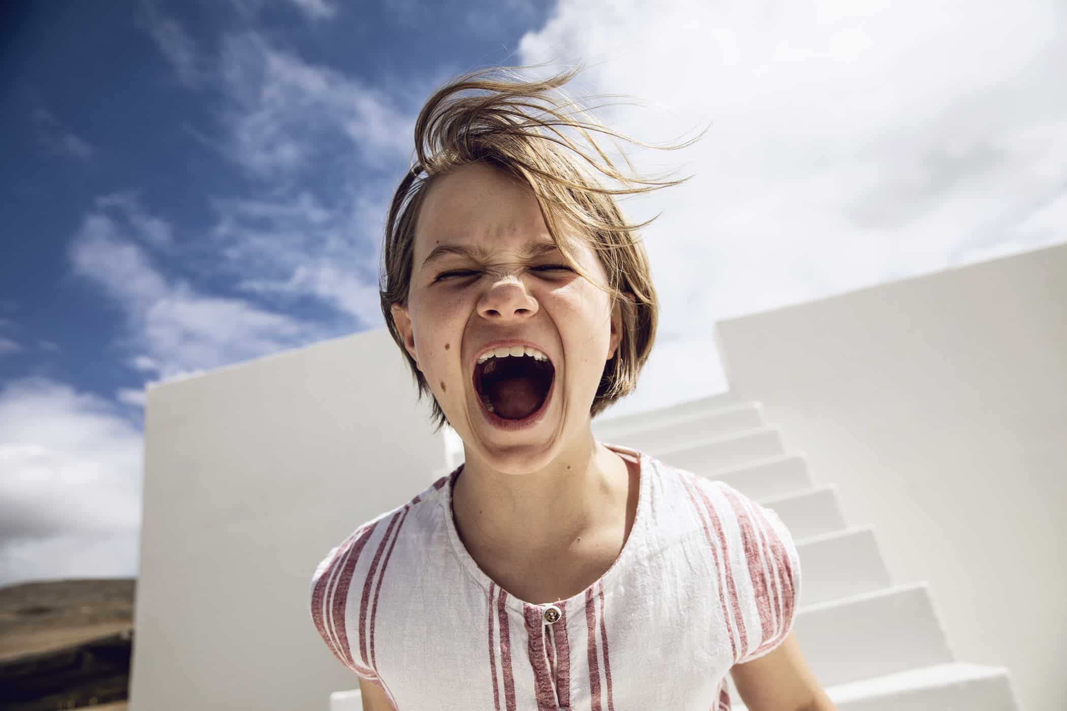 Expressive child yelling outdoors on a sunny day, illustrating emotional dysregulation, impulsive reactions, and behavioral challenges that can occur in ADHD and conduct disorders.