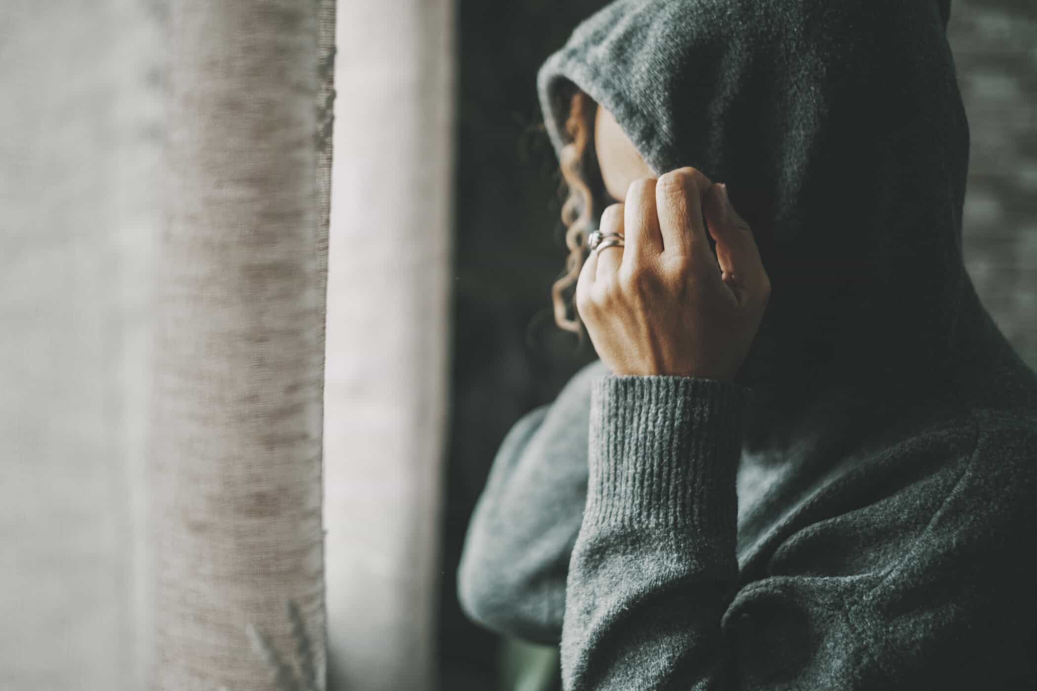 ADHS Masking symbolisiert durch eine Frau, die ihr Gesicht hinter einer Kapuze verbirgt