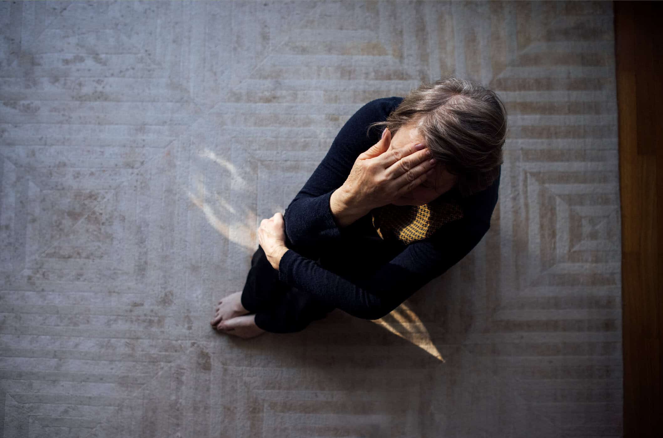 Frau sitzt zusammengesunken auf dem Boden und symbolisiert emotionale Erschöpfung bei ADHS und Depression