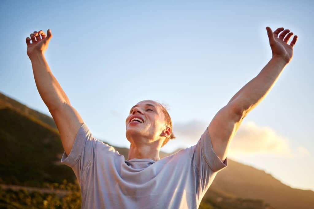 Mann streckt jubelnd die Arme in den Himmel – Symbolbild für Erleichterung im Umgang mit ADHS und Perfektionismus