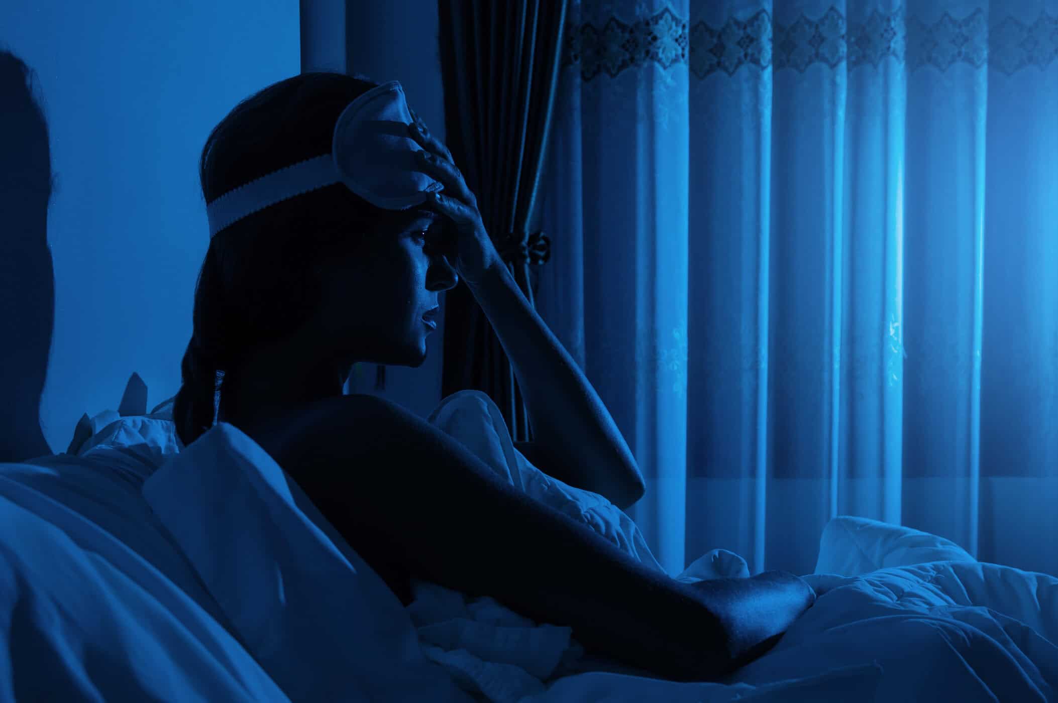 Frau sitzt gerade im Bett und guckt &auml;ngstlich - symbolisiert aufwachen nach Panikattacke Nachts