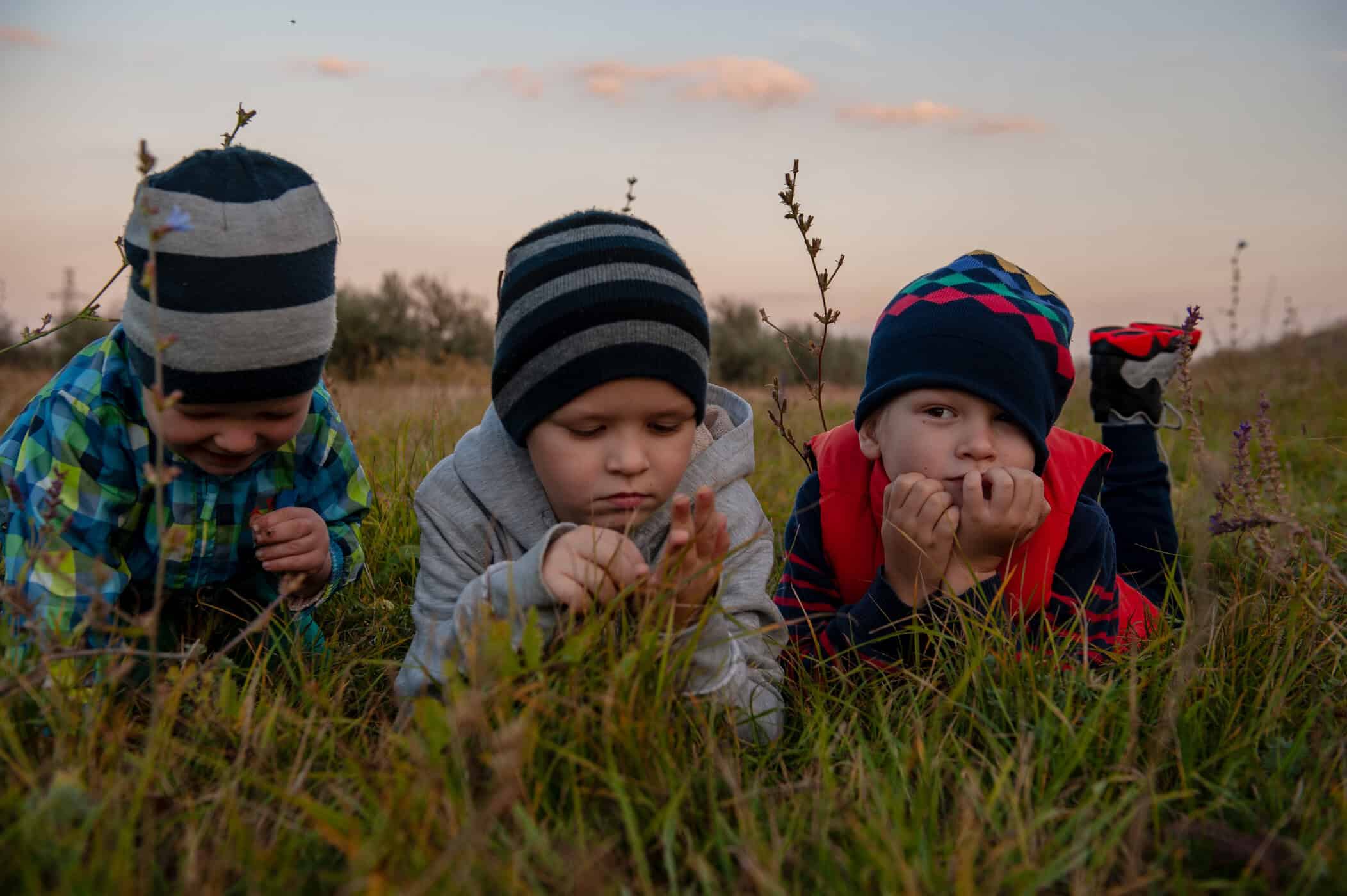 drei Jungs liegen auf der wiese, steht symbolisch daf&uuml;r Autismus bei Kindern erkennen