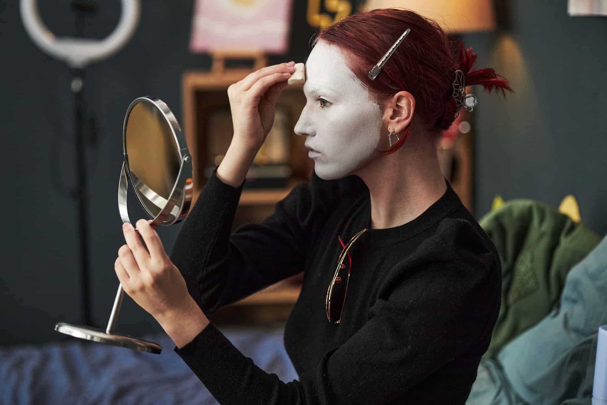 Frau schminkt ihr Gesicht weiß, symbolisiert Masking Autismus